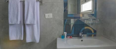 A bathroom with a white sink, a mirror, and two towels hanging on a rack.
