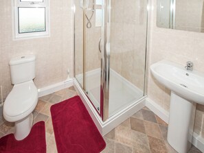 A bathroom with a glass-enclosed shower, a white toilet, and a sink.