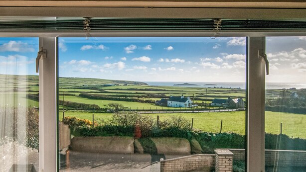 A view through a window of a rural landscape with rolling hills, a white building, and a clear sky. - 3 bedroom accommodation in Aberdaron (Aberdaron)