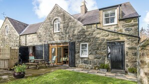 A stone house with a garden, a wooden door, and a window. - Bwthyn Stabal-QC1199 (Criccieth)