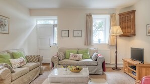 A living room with two sofas, a coffee table, a lamp, a TV, and a cabinet. - Bwthyn Stabal-QC1199 (Criccieth)