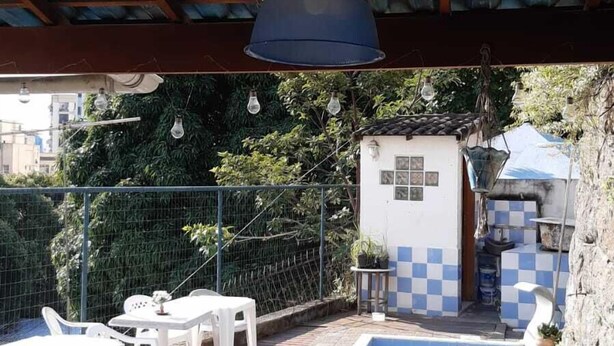 Une piscine dotée d’une terrasse carrelée, entourée de chaises en plastique blanches et d’une petite table.