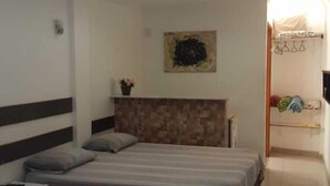 Une chambre à coucher avec deux lits, une tête de lit, un tableau et une salle de bain visible à travers une porte ouverte.