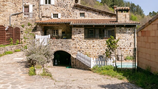 A stone building with a courtyard, a small archway entrance, and a fenced swimming area. - Château de Laulagnet - 3e avec piscine dans un écrin de verdure (Jaujac)