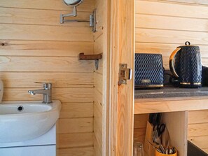 Ein Holzhütten-Interieur mit Waschbecken, Spiegel und Ablage für Tassen und Besteck.