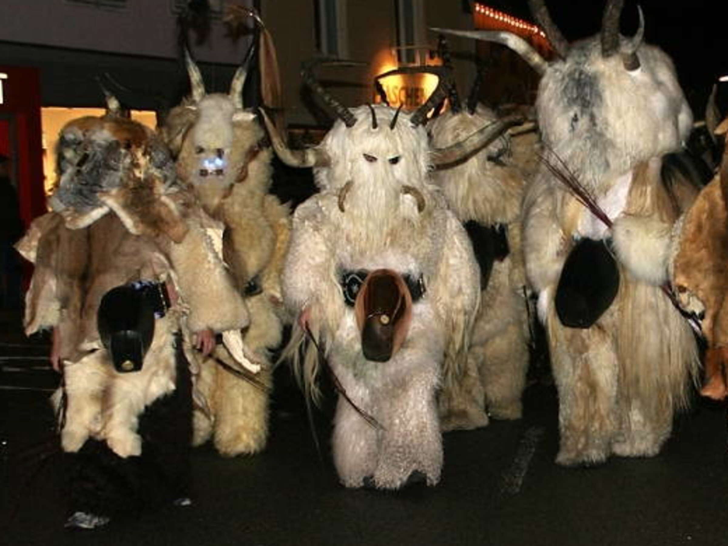 Um grupo de pessoas vestidas com fantasias de animais, com chifres e galhadas, em fila.