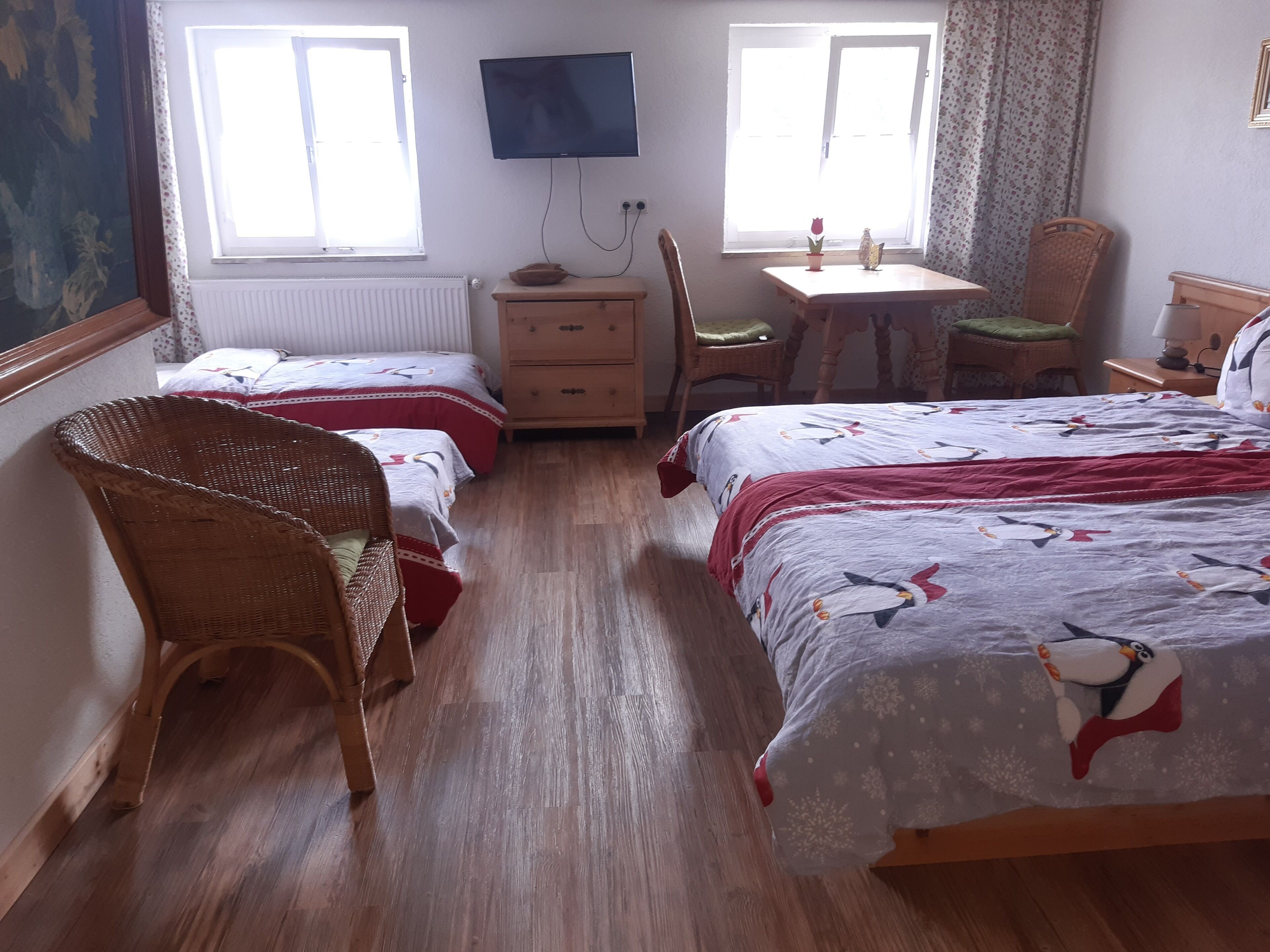 Un dormitorio con dos camas individuales, un aparador de madera, un televisor y una pequeña mesa con una silla.