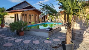 A wooden house with a swimming pool, surrounded by potted plants and pebbles. - Wellnesshof Müller Vorderburg (Rettenberg)