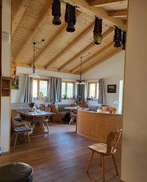 Una habitación amplia con vigas de madera, un comedor y una cocina.