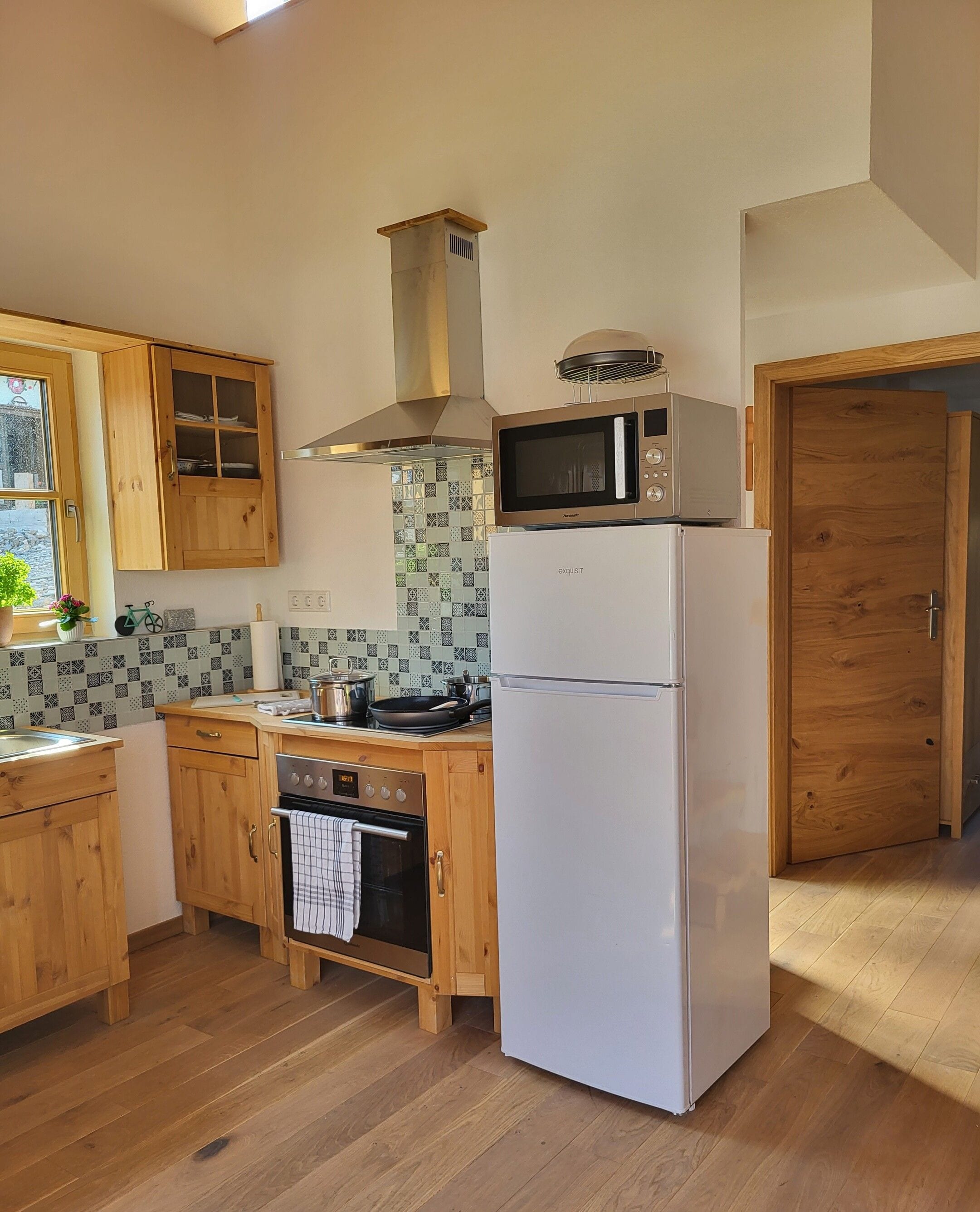 A kitchen with wooden cabinets, a stainless steel range hood, a microwave, an oven, and a refrigerator.