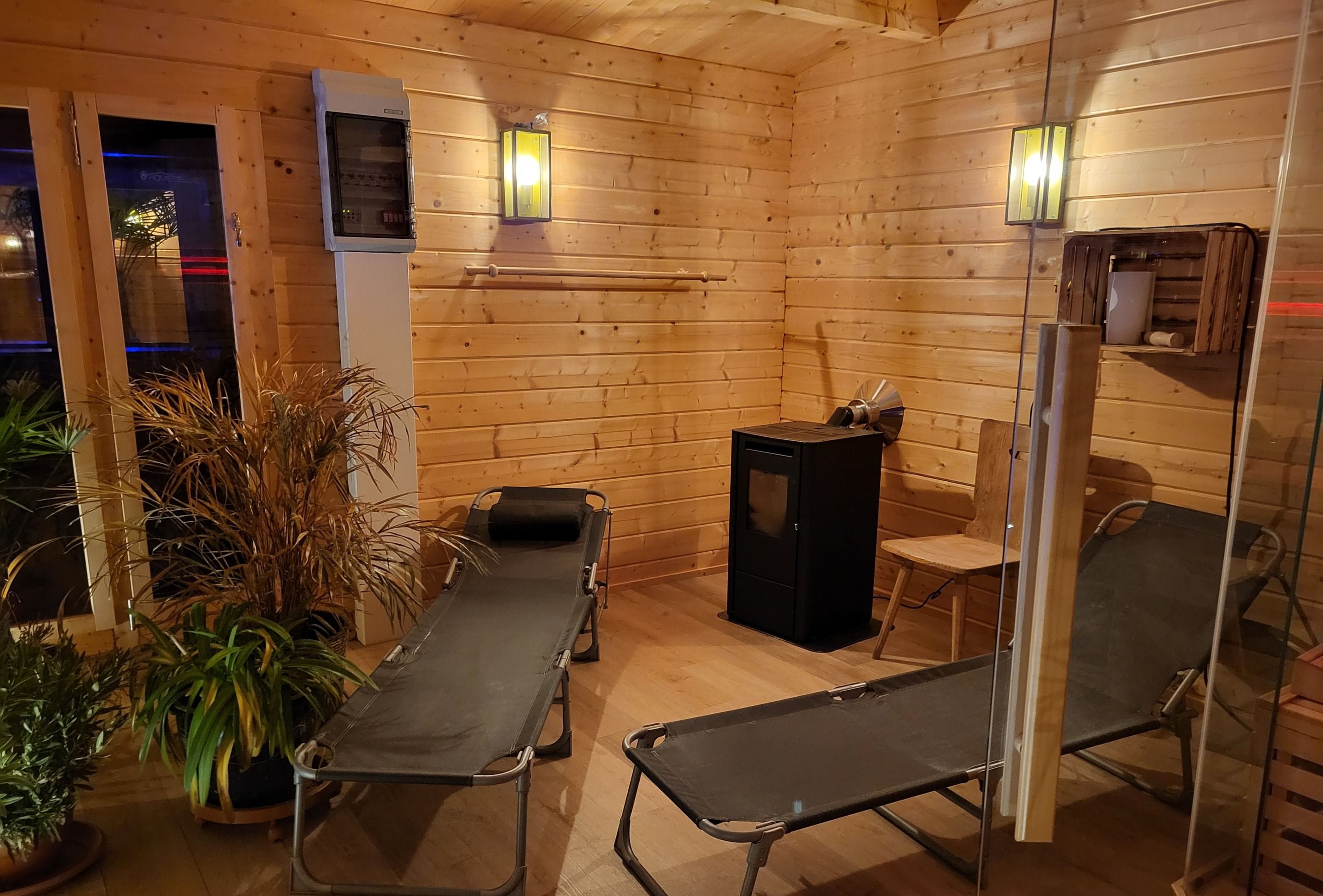 L’intérieur d’un chalet en bois comprend un sauna, une table de massage et une petite table avec une chaise.