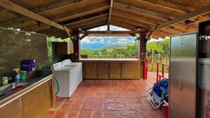 Cuina rústica amb rentadora, un rentaplat i vista a un paisatge verd.