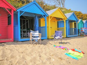 En række farverige strandhytter foran en sandstrand.