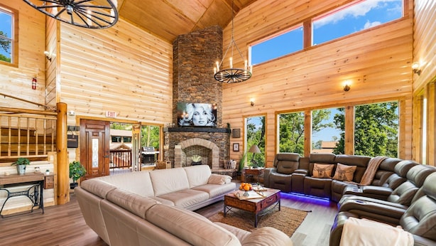 A spacious living room with a large sectional sofa, a fireplace, and a stone wall.