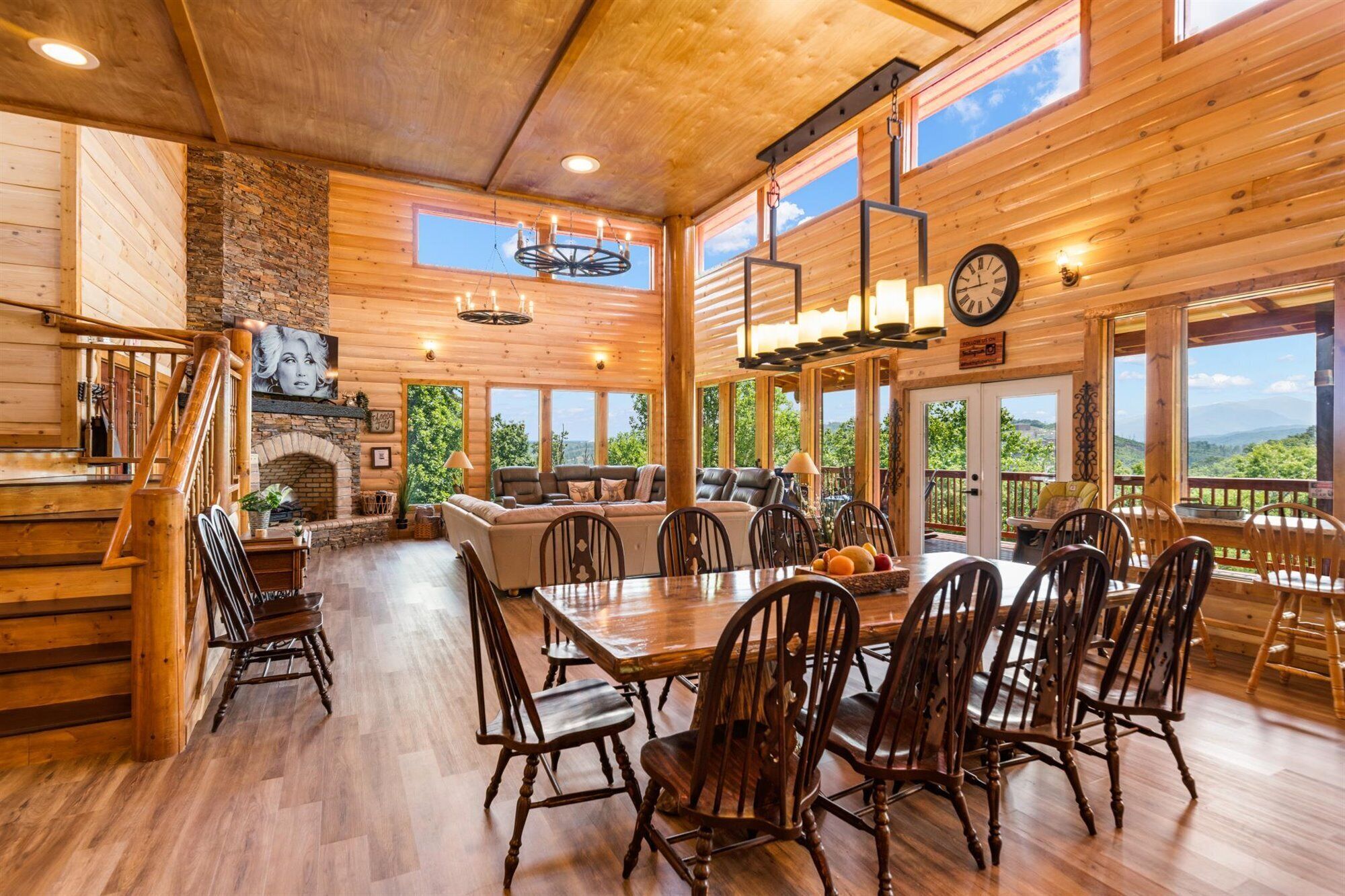 Une cabane en bois spacieuse, dotée d’un coin repas, d’une cheminée et de grandes fenêtres offrant une vue panoramique.
