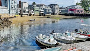 A waterfront property with a dock, boats, and colorful buildings. - Bearskin Neck Rental in the Heart of Rockport! Walk to Beaches + Restaurants! (Rockport)