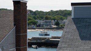 A view of a harbor with boats, a brick chimney, and a white building with a balcony. - Bearskin Neck Rental in the Heart of Rockport! Walk to Beaches + Restaurants! (Rockport)
