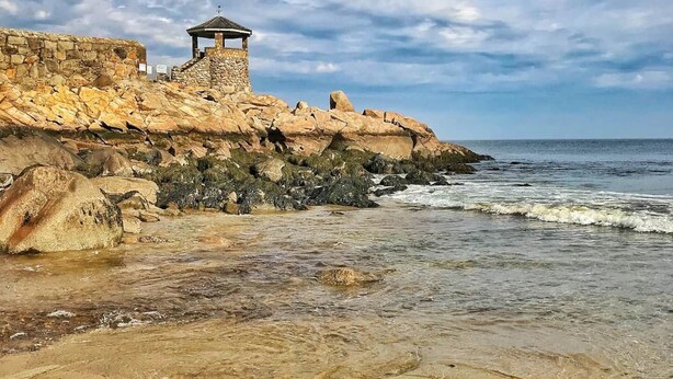A coastal area with a stone structure and a small pavilion overlooking the sea. - Bearskin Neck Rental in the Heart of Rockport! Walk to Beaches + Restaurants! (Rockport)