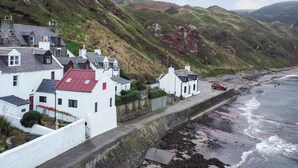 Un village côtier aux maisons blanches, doté d’un mur de pierre et bordé d’une plage.