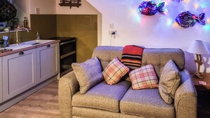 Un salon chaleureux avec un canapé, des coussins et une décoration lumineuse en forme d’étoile accrochée au mur.