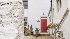 Une ruelle étroite, fermée par un portail en bois portant le numéro 4, mène à un immeuble avec une porte rouge et une enseigne sur laquelle on peut lire « The Window ».