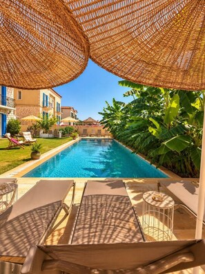 A swimming pool with lounge chairs and umbrellas, surrounded by greenery and buildings. - Alacati Fora Bella (Cesme)