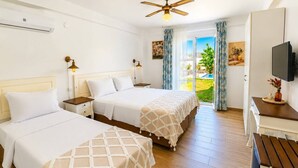 Habitación de hotel con dos camas, ventilador de techo, televisor y vistas al exterior.