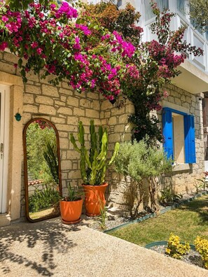 A stone building with a garden area featuring potted plants and a mirror. - Alacati Fora Bella (Cesme)