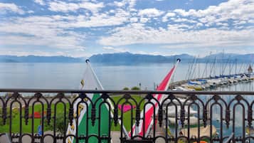 Una marina con barcos, cielo despejado y montañas al fondo.