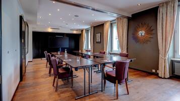 Ein Konferenzraum mit langem Tisch, Stühlen, einer großen Leinwand und einem dekorativen Wandelement.