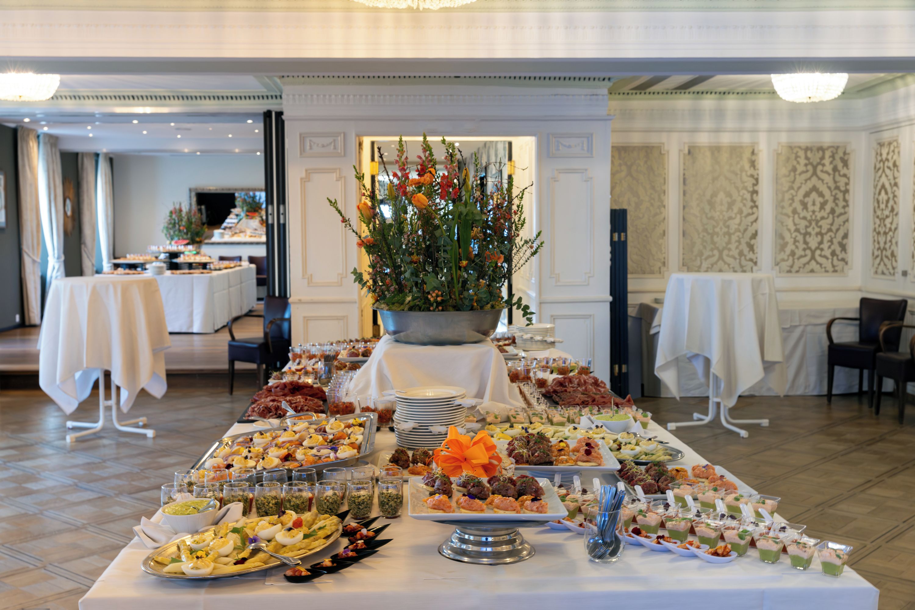 Une table de buffet garnie de divers plats et agrémentée d’un arrangement floral.
