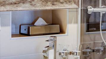 A bathroom with a white sink, a mirror, a towel rack, and a shower area.