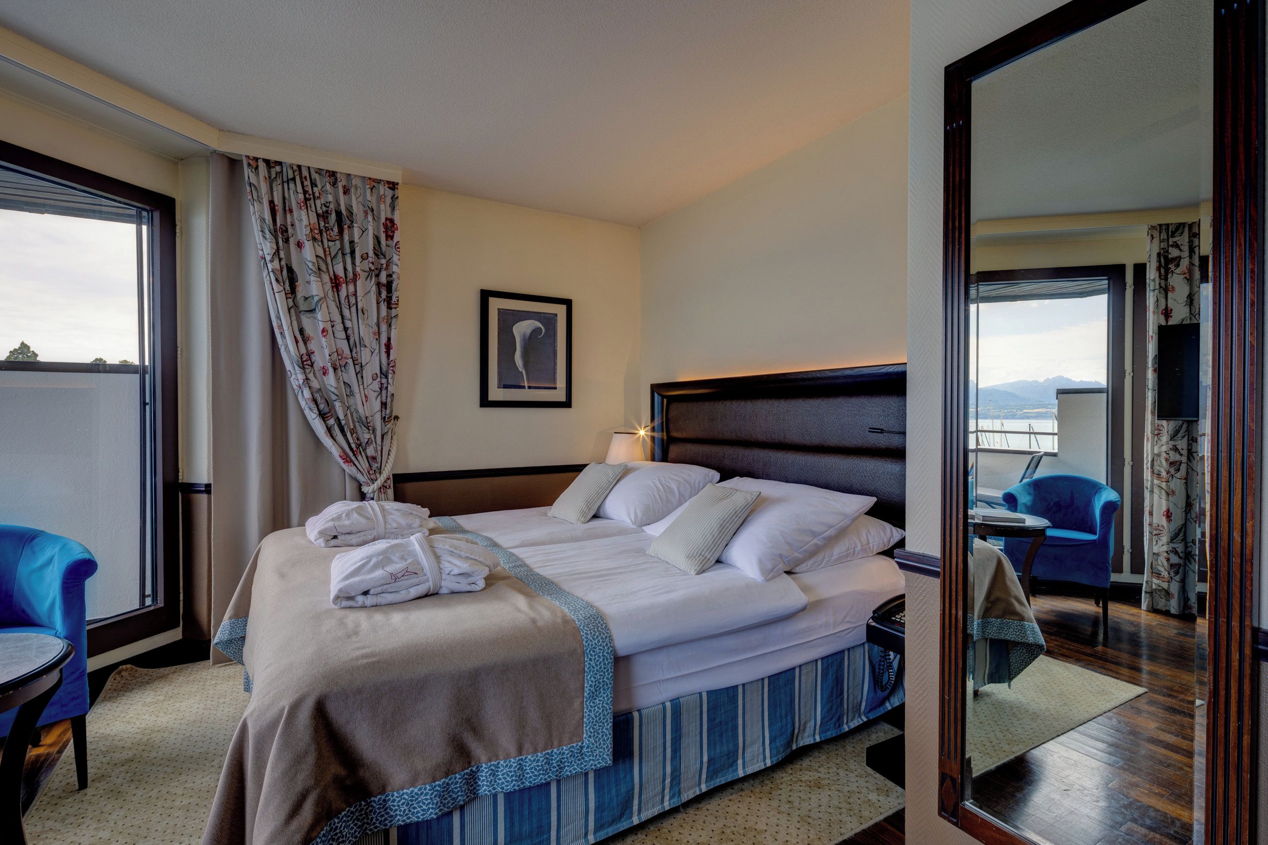 A hotel room with a bed, a chair, a desk, and a view of the outside.