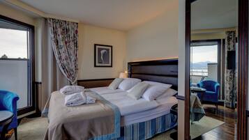 A hotel room with a bed, a chair, a desk, and a view of the outside.