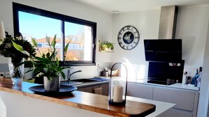 Une cuisine moderne avec un plan de travail en bois, un évier, une horloge et une fenêtre donnant sur l’extérieur.