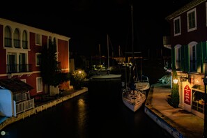 A nighttime marina with boats docked, a building with a sign 'LE TABAC', and a red building with green shutters. - L'Olivier, single-storey mazet, beautiful outdoor space and pergolas. (Le Plan de la Tour)