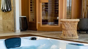 Ein Whirlpool mit einem Holztisch in der Nähe, einem Handtuchhalter und einer Glastür zu einem Raum.