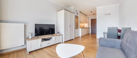Una sala de estar moderna con un televisor de pantalla plana, un sofá blanco y un sofá gris.