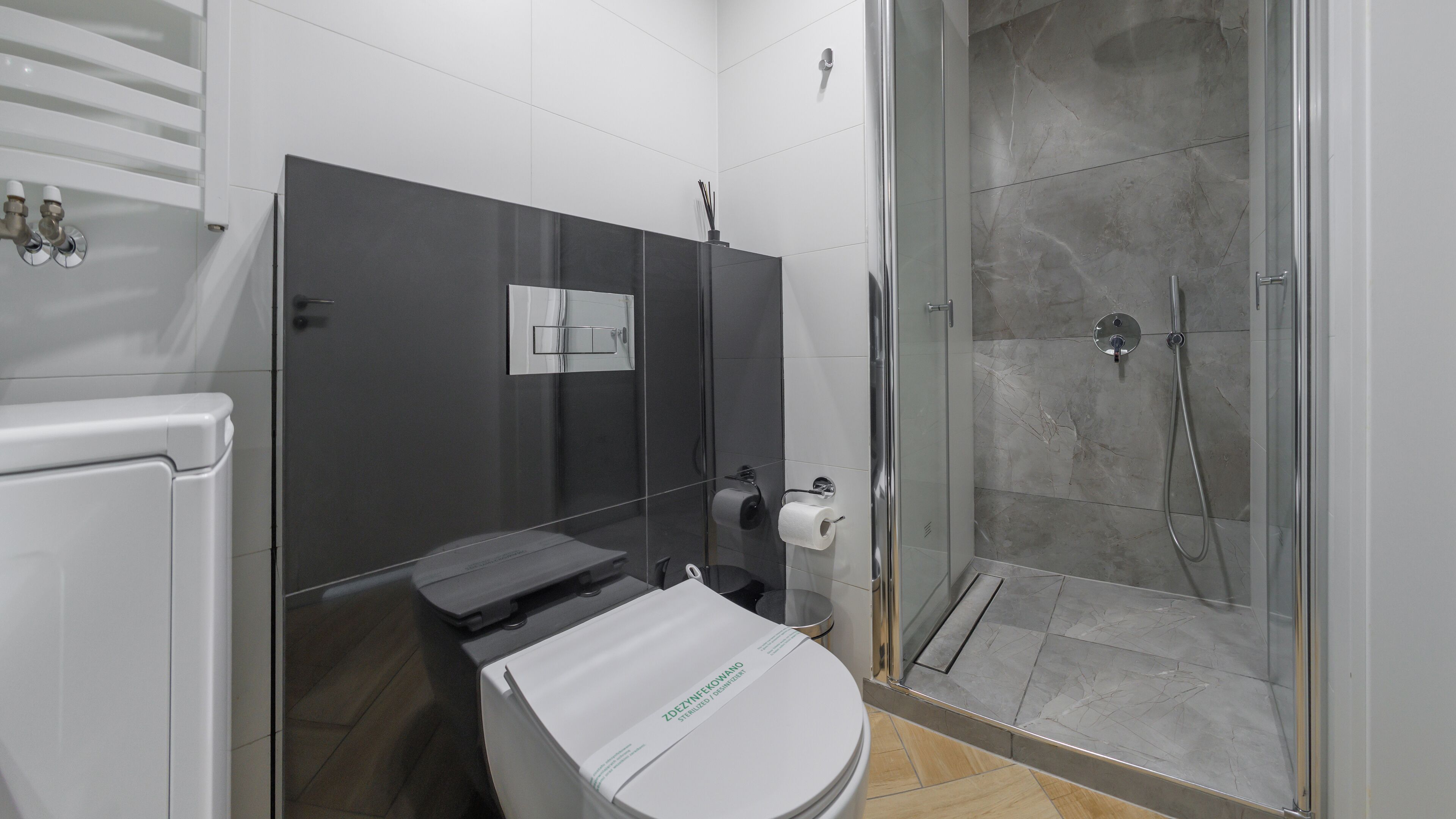 Een moderne badkamer met toilet, douche en wastafel.