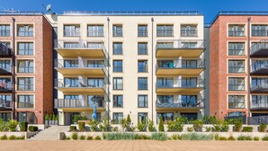 A multi-story residential building with balconies, a central entrance, and a landscaped front garden. - Apartamenty Sun & Snow Na Wydmach (Dziwnów)