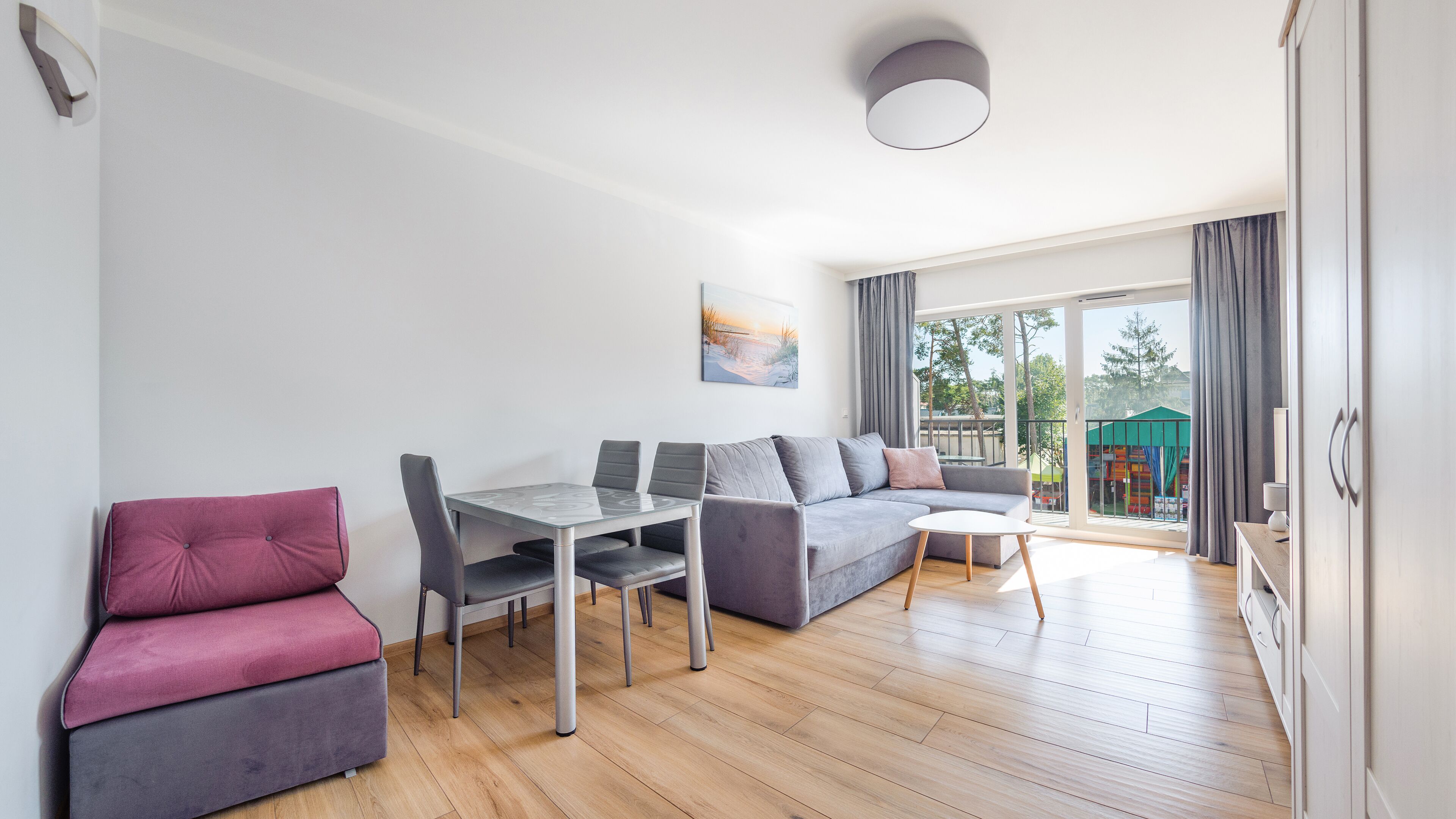 Una sala de estar moderna con comedor, un sofá, una mesita y vistas al exterior.