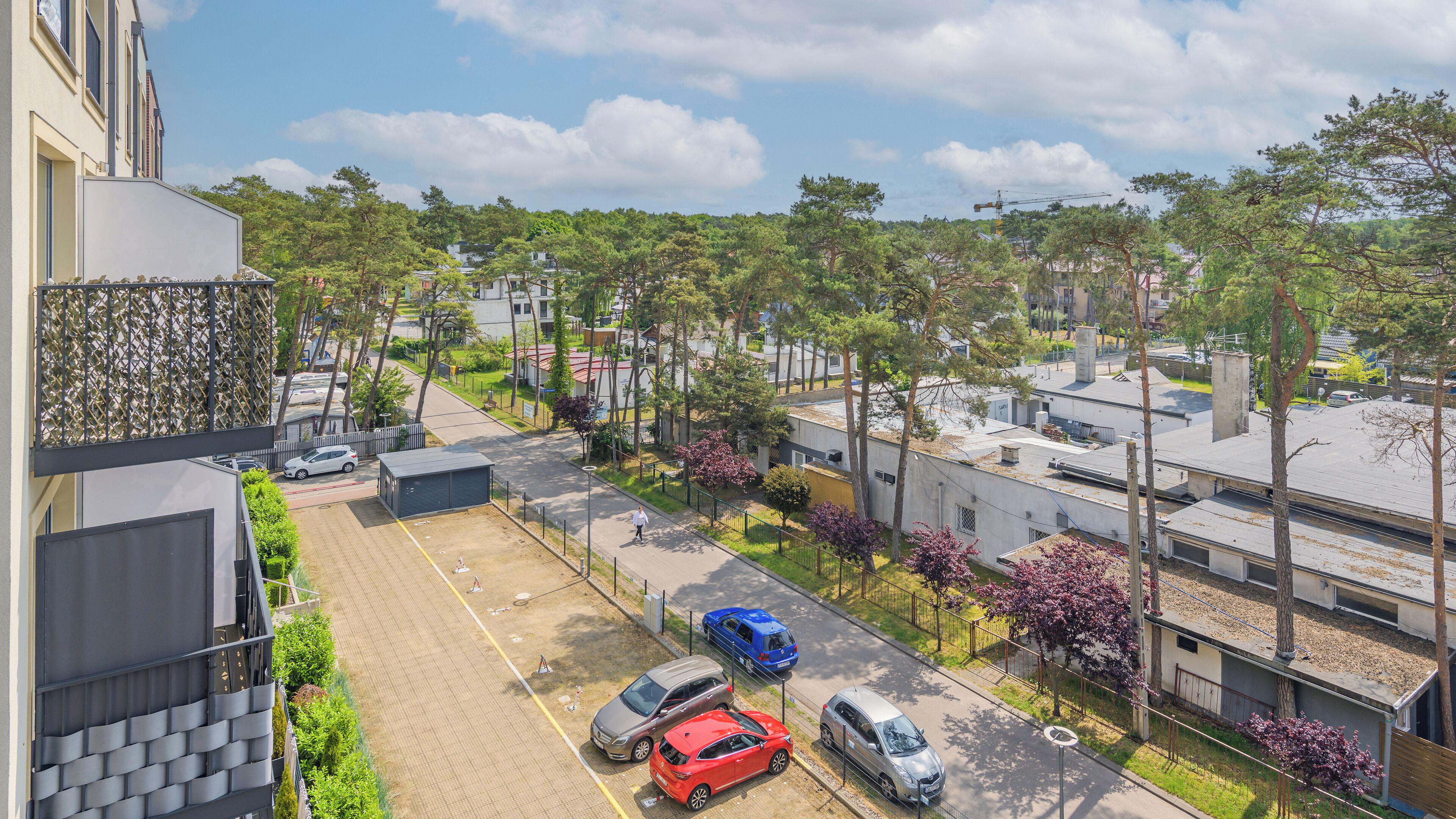 A residential area with parked cars, a pedestrian pathway, and trees.