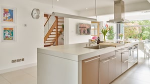 A modern kitchen with a central island, stainless steel appliances, and a view of the outdoors. - The Chase (Cheltenham)