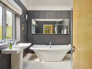 A modern bathroom with a freestanding bathtub, a pedestal sink, and a large mirror. - The Chase (Cheltenham)