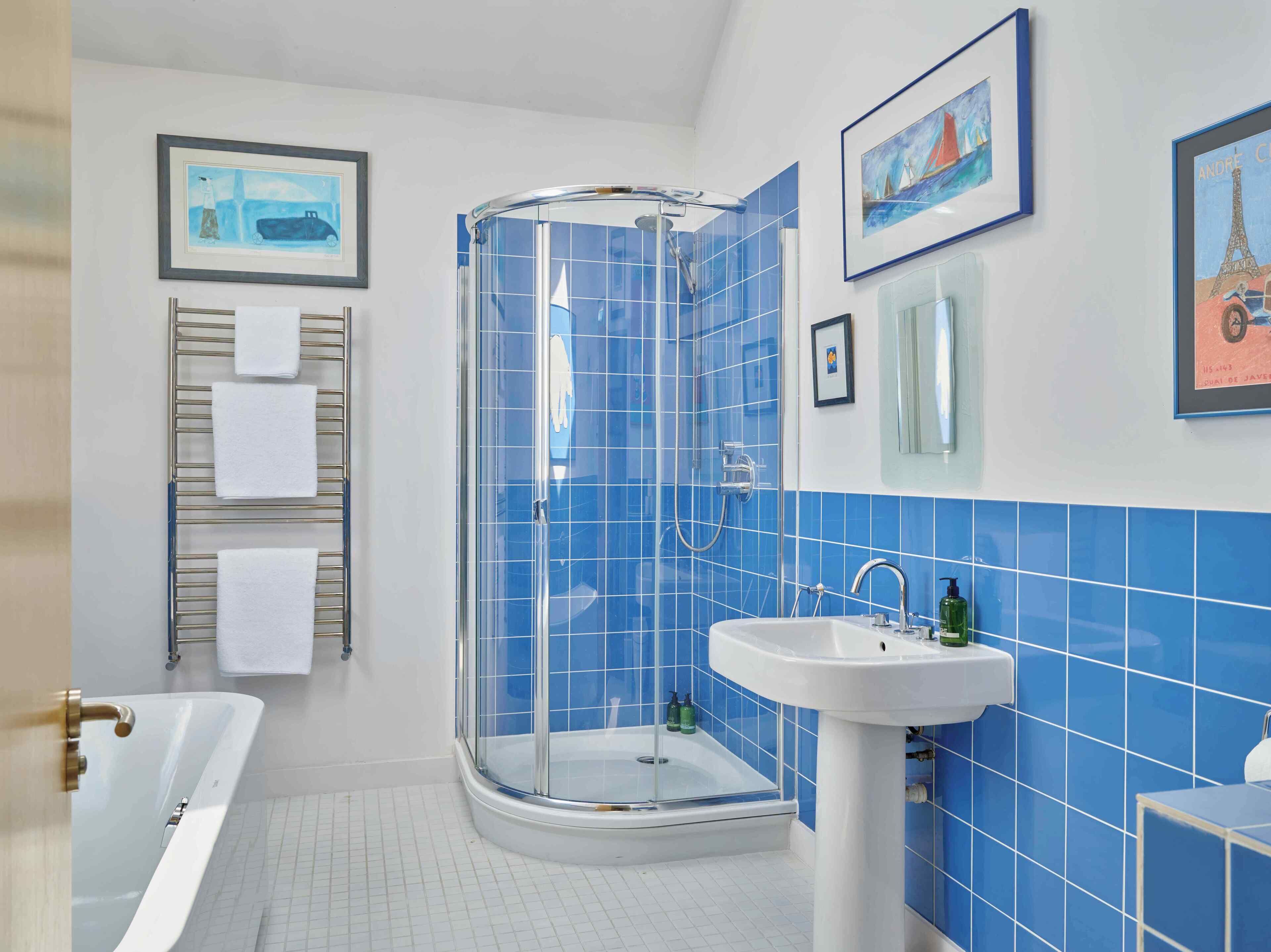 A modern bathroom with a glass-enclosed shower, a white bathtub, and a sink with a mirror.