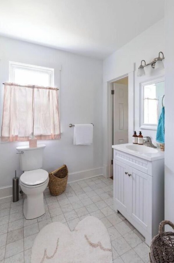 A bathroom with a toilet, sink, and window with curtains. - Charming Cottage on beautiful Farm & Vineyard (Keswick)