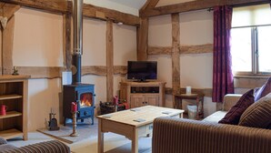 A cozy room with exposed wooden beams, a fireplace, a television, and a comfortable seating area. - 1 bedroom accommodation in Kingsland (Kingsland)