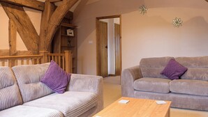 A cozy room with two striped sofas, a wooden table, and exposed wooden beams. - 1 bedroom accommodation in Kingsland (Kingsland)