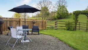 An outdoor patio with a table and chairs, a black umbrella, and a wooden fence. - 1 bedroom accommodation in Kingsland (Kingsland)