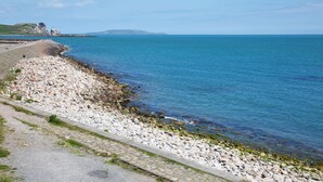 Une route côtière bordée d’une falaise rocheuse et offrant une vue dégagée sur la mer.